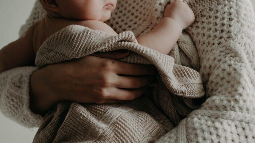 Bambino in braccio a un adulto, simbolo di cura e supporto emotivo.