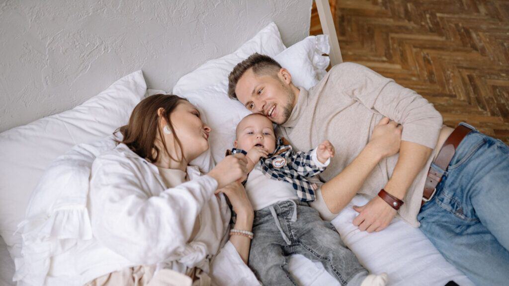 Ragazza, ragazzo e bambino sorridenti sul letto, momento di famiglia felice e serena.