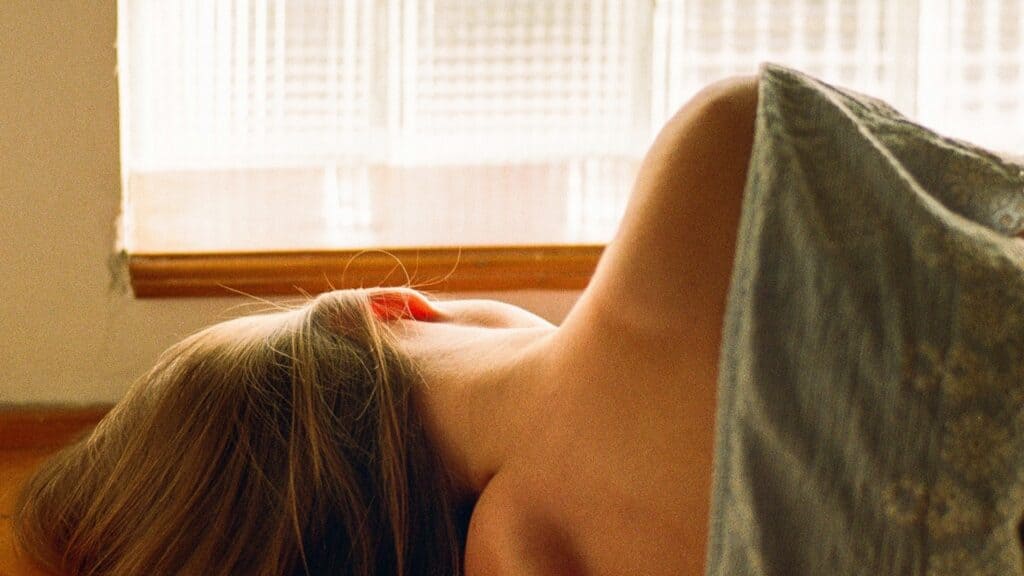 Donna sdraiata a letto vicino alla finestra, esausta