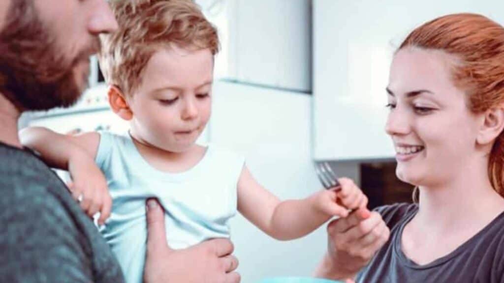 Genitori e bambino piccolo durante la pappa in cucina