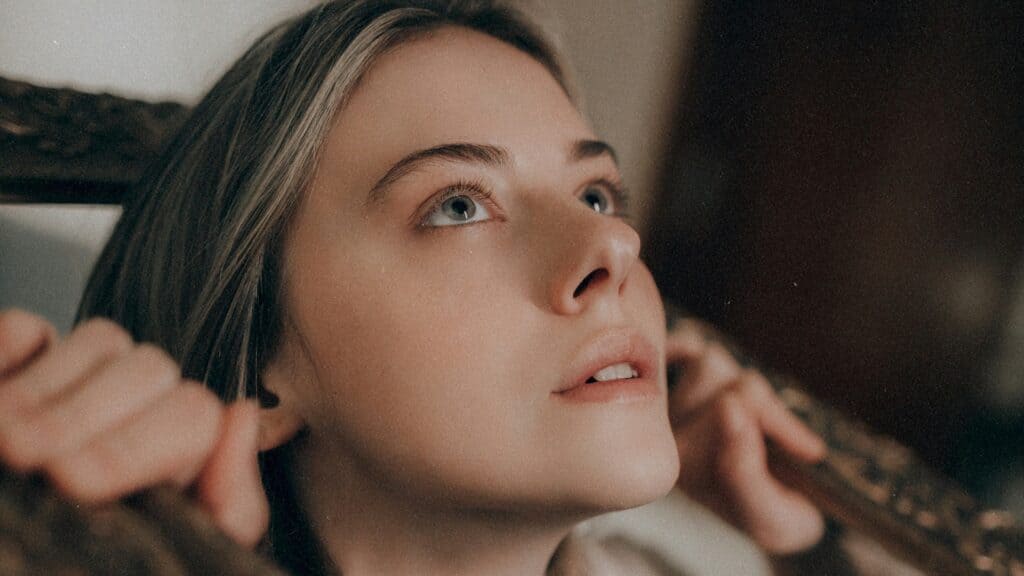 Giovane donna con lo sguardo rivolto verso l'alto, in un momento di ansia