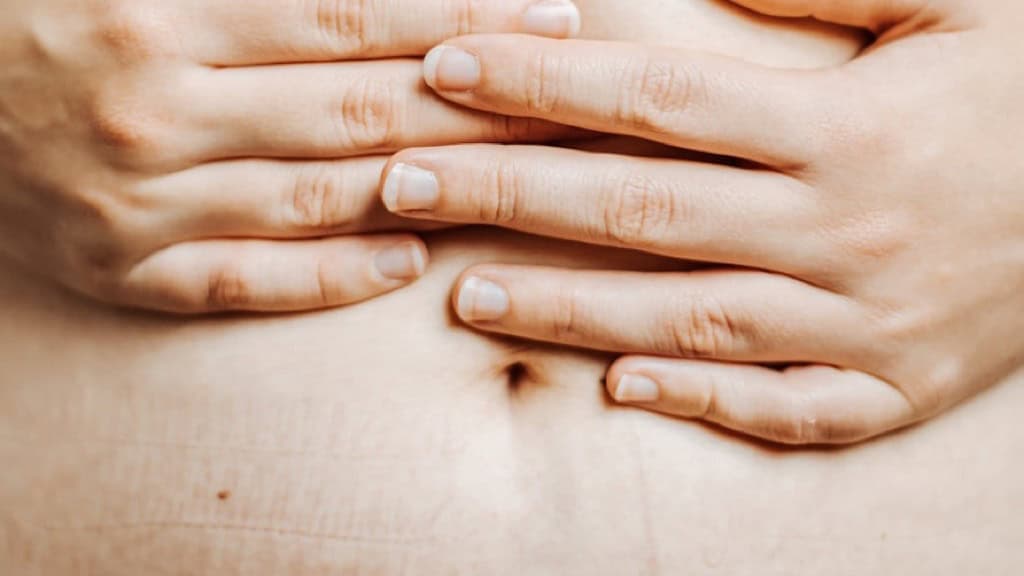Mani di donna appoggiate sulla pancia con le smagliature: il rapporto con l'immagine corporea